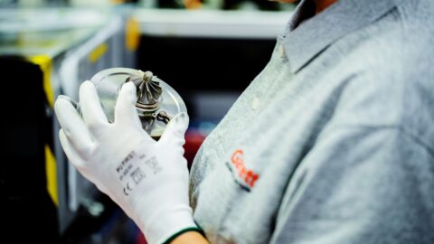 Garrett Employee holds a precise turbocharger part showing attention to detail