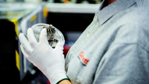 Garrett Employee holds a precise turbocharger part showing attention to detail